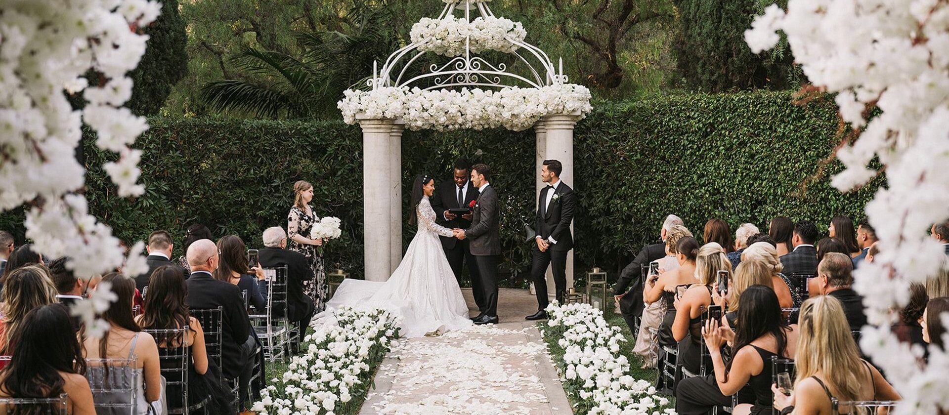 Wedding ceremony with an arch. Husband and wife are looking at each other.